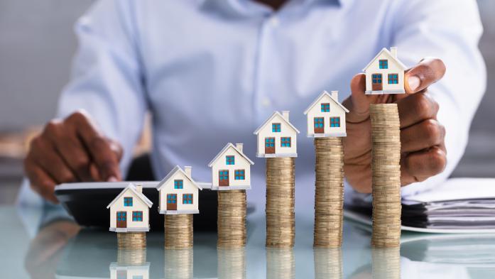 Higher and higher stacks of coins with small houses on top