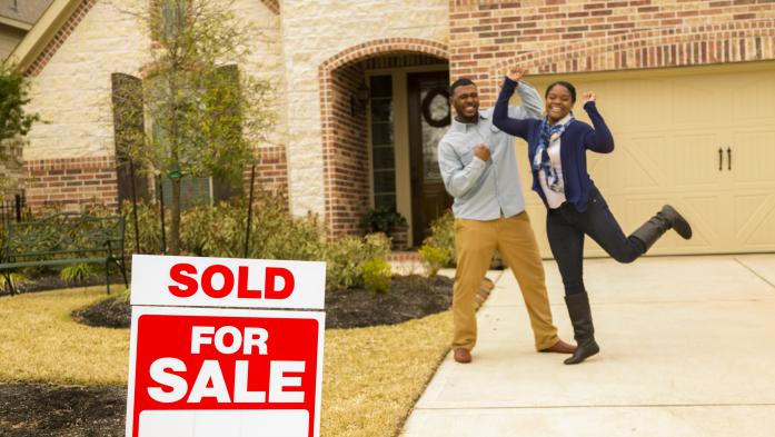Black man and woman jump for joy after buying new home