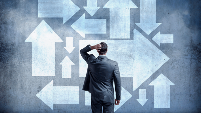 Image of a man looking at many arrows pointing in different directions, scratching head, confusion