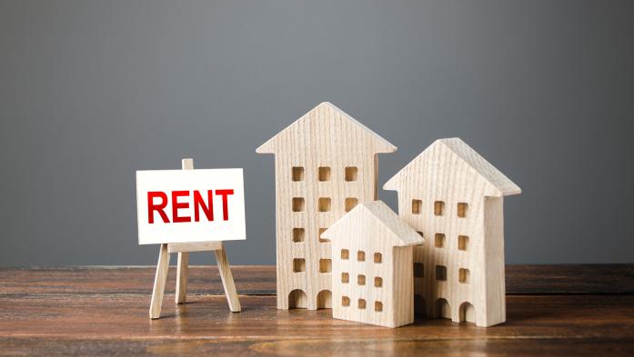 three wood block apartment buildings of different size with rent sign on easel