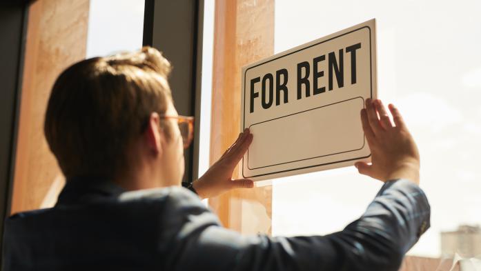 Many hangs a for-rent sign in his window