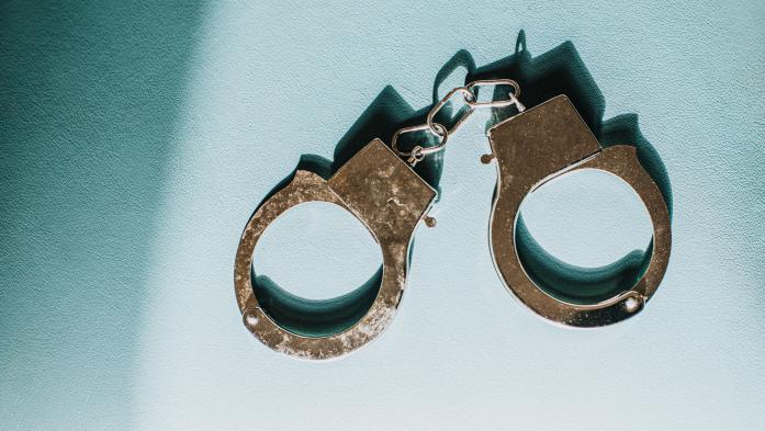 photo of metal handcuffs on a neutral blue background