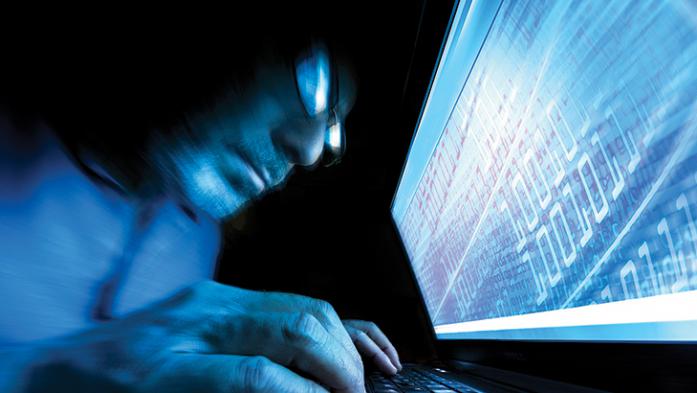 Photo of a man looking ominously at computer 
