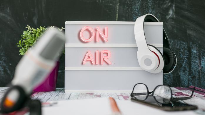 Photo of a sign that says On Air with headphones hanging on it.