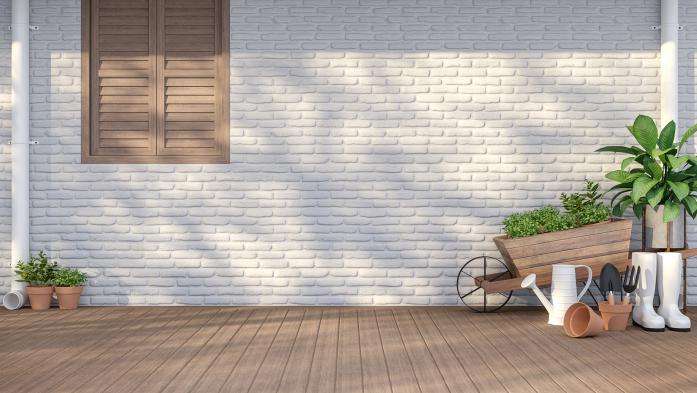 Home with white painted brick with a brown window and plants along the side