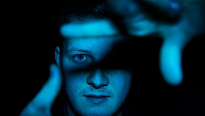 Man's face somewhat hidden within blue shadows