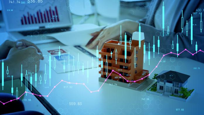 small model building and home  on a desk with a laptop and digital investment overlay
