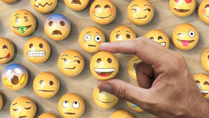 Man's hand picking an emoji among different expressions
