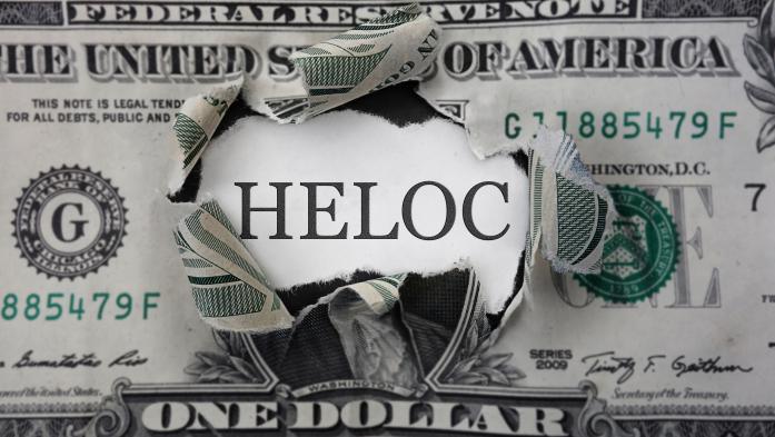 One dollar bill with a hole that says HELOC behind it